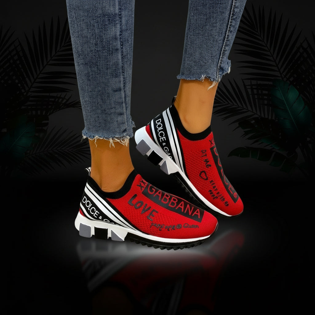 A pair of flat white sneakers with black text and design elements, worn by a person with visible jeans.