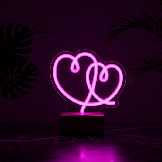 A neon lamp with the shape of two hearts glowing in pink color on a purple background.