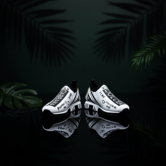 A pair of flat white sneakers with black text and design elements, worn by a person with visible jeans.