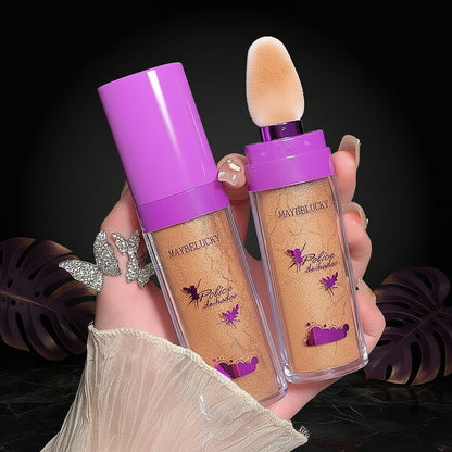 Maybelline foundation bottles with a purple cap held by a hand against a dark background.