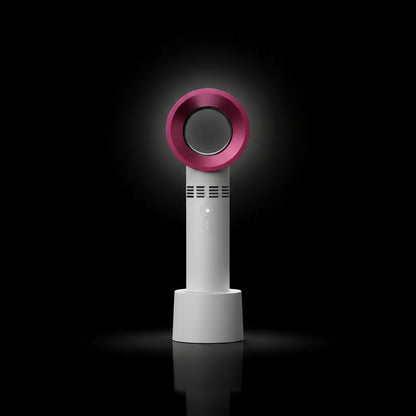 A handheld rechargeable eyelash blower with a pink circular mouthpiece and a teal blue body, being held in a person's hand.